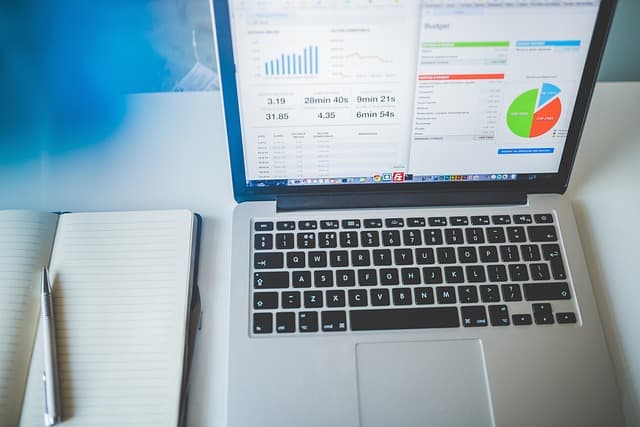 Professional working across multiple digital tools on laptop